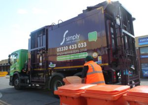 Simply Waste Solutions 2019 plate Food and Glass waste collection truck, a Toploader. Truck driver wheelie orange 240l food bin over to truck to be lifted